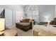 Sitting area in bedroom with cozy couch, ottoman, bright window, and neutral tones at 2 Sunrise Ct., Carolina Shores, NC 28467