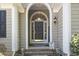 Close up of charming front door with arched entryway, decorative plants, and stone pathway at 2 Sunrise Ct., Carolina Shores, NC 28467
