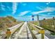 Wooden boardwalk leading to sandy beach with dunes and clear blue sky at 210 75Th Ave. N # 4034, Myrtle Beach, SC 29572