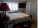 Relaxing bedroom featuring a decorative quilt, plantation shutters, a ceiling fan and a mounted television at 305 N Hillside Dr. N # 103, North Myrtle Beach, SC 29582