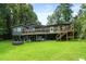 A home's rear exterior boasts a large wood deck overlooking a well-manicured yard and pond at 532 Medcalf Dr. Sw, Sunset Beach, NC 28468