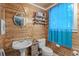 Cozy bathroom featuring rustic wood-paneled walls, a bright blue curtain, and a cute mermaid shelf at 532 Medcalf Dr. Sw, Sunset Beach, NC 28468