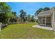Lush backyard featuring a lawn, picket fence, mature trees, and a screened porch at 615 Woodbine Ct., Myrtle Beach, SC 29579
