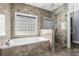 Modern bathroom with tub, glass shower, and neutral stone tile surround at 615 Woodbine Ct., Myrtle Beach, SC 29579