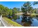 Scenic pond view with a white picket fence and lush greenery in the background at 615 Woodbine Ct., Myrtle Beach, SC 29579
