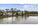 Condo buildings on a serene lake with treeline along the water's edge under a partly cloudy sky at 627 Bonaventure Dr. # 201, Myrtle Beach, SC 29577