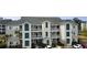 Exterior of a three story condo featuring a light colored facade with teal shutters, cars in front and palm trees at 1100 Commons Blvd. # 606, Myrtle Beach, SC 29572