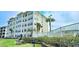 Exterior view of a multi-story condo complex with a waterfront view, including palm trees and grilling area at 1100 Commons Blvd. # 606, Myrtle Beach, SC 29572
