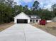 New single-story home with white siding, stone accents, concrete driveway, and a forest backdrop at 1274 Pinetucky Dr., Galivants Ferry, SC 29544