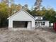 A charming new home shows white siding, a black roof, stone accents, and an attached two-car garage at 1274 Pinetucky Dr., Galivants Ferry, SC 29544