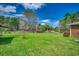 Large grassy backyard with mature trees, vibrant azaleas, and a partial view of the brick house at 144 Pink Dogwood Dr., Loris, SC 29569