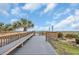 Beach boardwalk with palm tree, seating and shower area on a sunny day at 2507 S Ocean Blvd. # 802, North Myrtle Beach, SC 29582
