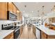 View of the kitchen showcasing wood cabinets, stainless steel appliances, quartz countertops, and sightlines to living spaces at 393 Sun Colony Blvd., Longs, SC 29568