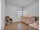 Cozy bedroom featuring a stylish wallpaper accent wall, crib, and wood-look flooring at 4105 Da Vinci Dr., Myrtle Beach, SC 29579