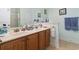 Bathroom with double sinks and wooden cabinets, complemented by light blue walls and a large mirror at 5012 Prato Loop # 5012, Myrtle Beach, SC 29579