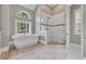 Elegant bathroom with a soaking tub, separate shower, and marble tile, perfect for relaxation at 653 Whispering Pines Ct., Murrells Inlet, SC 29576