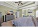 Bright primary bedroom with tray ceiling, ceiling fan, television, and sitting area at 124 Mesa Raven Dr., Longs, SC 29568