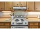 Close-up of the white stovetop, hood, and wooden cabinets in the kitchen at 1581 S Waccamaw Dr. # 303, Murrells Inlet, SC 29576