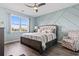 This main bedroom boasts a modern accent wall, a ceiling fan, and a large window with neighborhood views at 1612 Cosmos Lane, Myrtle Beach, SC 29577