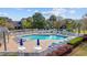 A refreshing fenced pool area features ample lounge chairs, tables with umbrellas, and lush landscaping at 12 Spartina Ct. # 2, Pawleys Island, SC 29585