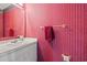 Red bathroom with a vanity, golden hardware, and a decorative pink and red wallpaper at 1213 Oak St., Conway, SC 29526