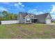 Rear exterior view of a charming one-story home with gray siding and a large backyard with a white fence at 1794 Graham Rd., Aynor, SC 29544