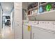 Convenient laundry area featuring a white washer and dryer, along with shelving for storage and adjacent living space at 1801 N Ocean Blvd. # O-4, North Myrtle Beach, SC 29582
