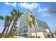 Beautiful high-rise condo building with tropical landscaping, palm trees, and clear blue sky at 201 74Th Ave. N # 1128, Myrtle Beach, SC 29572
