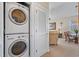 Efficient laundry closet with stacked washer and dryer, next to a view of the spacious and furnished living room at 5751 Oyster Catcher Dr. # 234, North Myrtle Beach, SC 29582