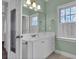 Well-lit bathroom featuring a white vanity, decorative mirrors, and natural light from the window at 9278 Nw Checkerberry Square, Calabash, NC 28467