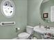 Charming powder room with pedestal sink, oval window, and calming green walls at 9278 Nw Checkerberry Square, Calabash, NC 28467