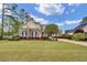 Beautiful brick home featuring mature landscaping, a sprawling green lawn, and elegant black shutters at 9278 Nw Checkerberry Square, Calabash, NC 28467