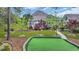 Well-manicured backyard featuring putting green, lush lawn, mature trees, and beautiful landscaping at 152 Creek Harbour Circle, Murrells Inlet, SC 29576