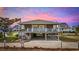 Two-story beach house with a large deck and covered parking underneath the house under a colorful sky at 202 56Th Ave. N, North Myrtle Beach, SC 29582