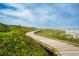 Scenic boardwalk winding through greenery with ocean and buildings visible in the distance on a sunny day at 4771 Wild Iris Dr. # 204, Myrtle Beach, SC 29577