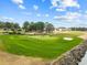 Scenic aerial of green golf course with golfers, mature trees, sand traps, and bodies of water under a blue sky at 4771 Wild Iris Dr. # 204, Myrtle Beach, SC 29577