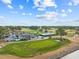 Aerial view of golf course with clubhouse, well-manicured greens, mature trees, and a blue sky with scattered clouds at 4771 Wild Iris Dr. # 204, Myrtle Beach, SC 29577