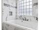 A luxurious bathroom features a soaking tub, marble tiling, and a glass block window for natural light at 601 Seth Ln., Longs, SC 29568