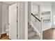Carpeted stairs with white risers and wooden handrail, leading to an upper level with view to the kitchen at 1095 Nw Forest Bend Dr., Calabash, NC 28467