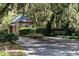 A charming brick guardhouse and signage welcome you to Wedgefield Plantation, framed by picturesque trees at 120 Wraggs Ferry Rd., Georgetown, SC 29440