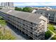 Long shot of a multi-story condo with balconies and outdoor stairs, situated on a parking lot at 212 Maison Dr. # M 303, Myrtle Beach, SC 29572