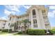 Beautiful multi-story condo building featuring white trim, balconies, palm trees, and manicured landscaping at 4409 Eastport Blvd. # E2, Little River, SC 29566