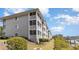 Exterior of condo building featuring enclosed porches and manicured landscaping at 4409 Eastport Blvd. # E2, Little River, SC 29566