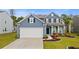 Charming blue two-story home featuring a two-car garage, black shutters, and manicured landscaping at 808 Wild Leaf Loop, Conway, SC 29526
