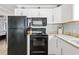 Galley kitchen featuring white cabinets, stone countertops, and black appliances at 811 N Ocean Blvd. # 401, Surfside Beach, SC 29575
