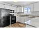 Kitchen features white cabinets, stone countertops, and black appliances at 811 N Ocean Blvd. # 401, Surfside Beach, SC 29575