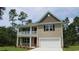 Charming two-story home with a covered porch and attached garage, set against a backdrop of lush trees at 847 Ireland Dr., Longs, SC 29568