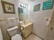 Bright bathroom with a single sink vanity, toilet, and coastal-themed artwork and decor at 9820 Queensway Blvd. # 607, Myrtle Beach, SC 29572