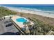 Aerial view of a community pool near the beach, surrounded by palm trees and lush greenery, and a parking lot at 9820 Queensway Blvd. # 607, Myrtle Beach, SC 29572