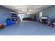 Spacious garage with blue walls and floor, multiple lawnmowers, and storage shelves at 1210 Horry Rd., Aynor, SC 29511